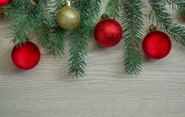 Composición navideña de ramas de abeto y bolas rojas, doradas sobre tablas de madera — Foto de Stock