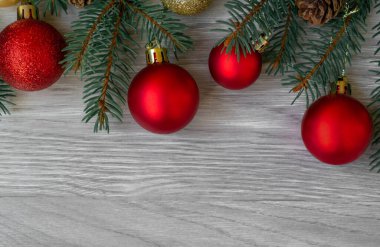 Noel kompozisyonu köknar dalları, köknar kozalakları ve ahşap bir arka planda kırmızı toplar