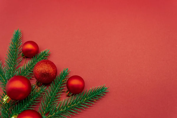 Bolas rojas de Navidad con ramas de abeto sobre fondo rojo — Foto de Stock