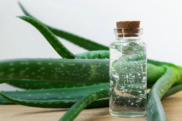 Glazen fles aloë vera gel met plantenbladeren op houten ondergrond Rechtenvrije Stockfoto's