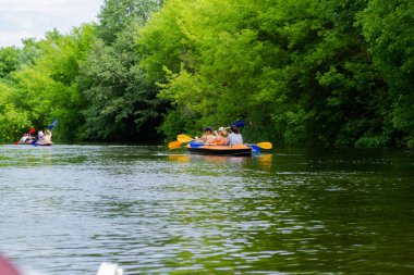 Yazın nehirde kayak yapmak. Güzel doğanın arka planında bir grup insanın kano üzerinde görüntüsü