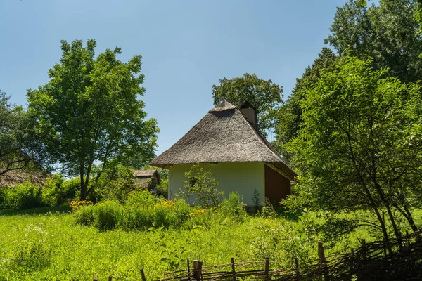 Velha, medieval, tradicional casa rural ucraniana com cerca de vime e jardim com flores. — Fotografia de Stock