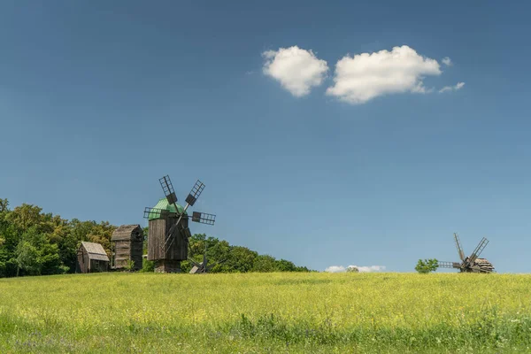 Antiguo molino de viento en un prado verde, campo. Cielo azul con nubes blancas. — Foto de Stock