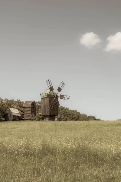 Antiguo molino de viento en un prado verde, campo. Cielo azul con nubes blancas. Foto vieja. — Foto de Stock