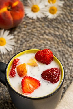 Siyah seramik bardakta çilekli yoğurt, şeftali ve chia. Sağlıklı ve lezzetli bir kahvaltı..