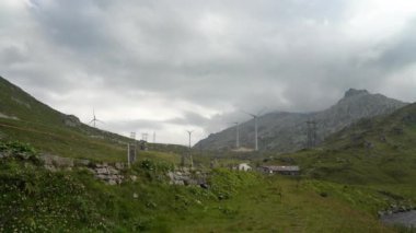 Rüzgar türbinleri, yenilenebilir enerji teknolojileri. Dağların ve bulutların arka planında dönen yel değirmenleri. Yeşil rüzgar enerjisi.