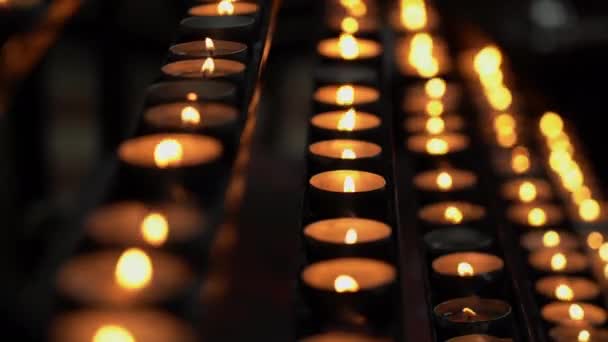 Detailní záběry hořících svíček v kostele na tmavém pozadí. — Stock video