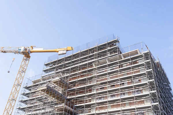 Edificio en construcción con armadura y grúa . — Foto de Stock