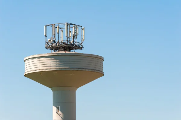 Torre del tanque de agua coronada con un repetidor de antenas de teléfono —  Fotos de Stock