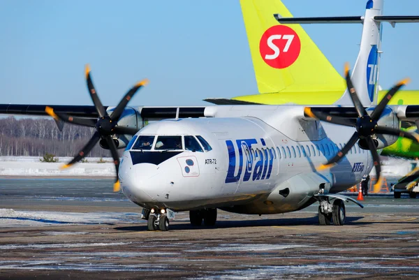 Пассажирский самолет ATR-72 компании UTair-Express на стоянке и хвост Airbus A320 компании S7 — Stok fotoğraf