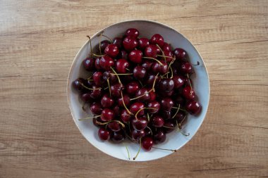 Tahta bir masada kiraz dolu büyük bir kase.