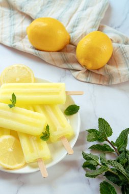 Düz bir buzda limon patlaması ve arka planda taze limon.