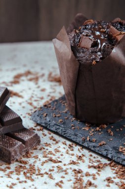 Çikolata parçacıkları serpiştirilmiş siyah bir tabakta çikolatalı keklerin yakın plan planı.