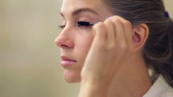 Wanita cantik muda menerapkan riasan di kelopak mata dengan kuas — Stok Video