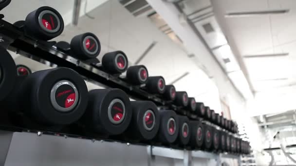 Mancuernas deportivas de goma en el club deportivo moderno. Equipo de entrenamiento con pesas. Cámara en movimiento — Vídeos de Stock