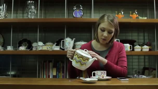 Νεαρή γυναίκα ρίχνει τσάι από την τραπεζαρία τραπέζι στο σπίτι — Αρχείο Βίντεο