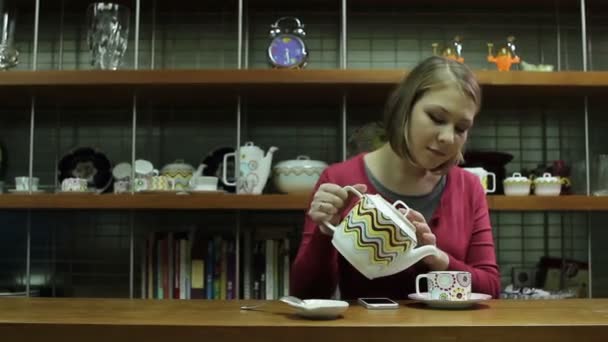 Young woman  pouring tea by dinning table and watching on cellphone — Stock Video