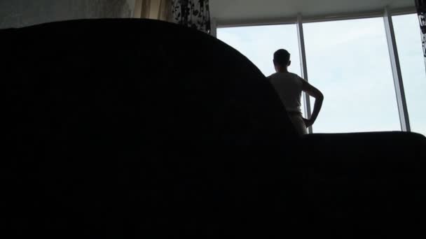 Silhouette of  man looking out the window in the flat — Stock Video