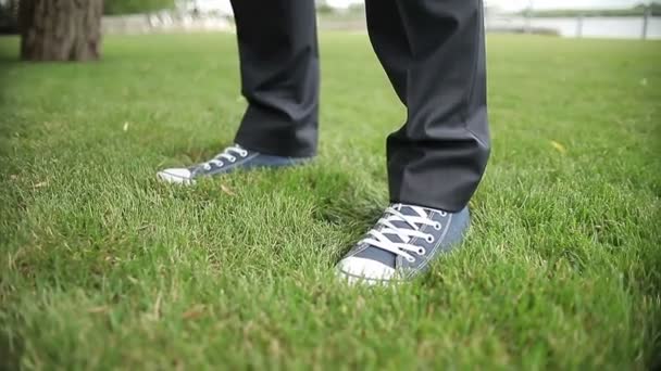 De cerca, los pies en zapatillas de deporte se paran en la hierba — Vídeo de stock