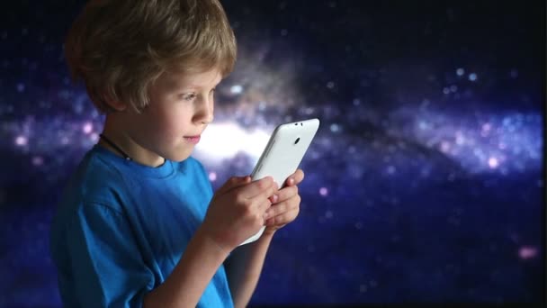 タブレット pc で遊ぶ少年。宇宙の空の背景の上に座って手で少年とタブレット デバイスのクローズ アップ — ストック動画