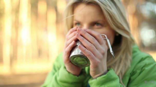 Camper vrouw camping drinken thee en warme dranken in bos. Mooie lachende gelukkig Kaukasische vrouwelijke model in outdoor activiteit. — Stockvideo