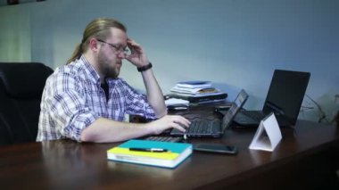 Ofiste, steadicam dizüstü bilgisayar üzerinde çalışan genç adam