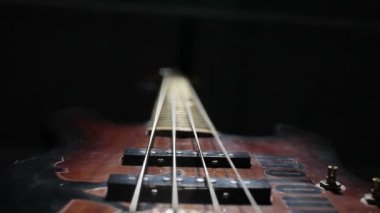 Bas gitar teli titreşimli. Yakın çekim. Siyah arka plan.
