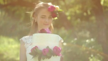 Güzel gelin bir çiçek outdoors ile bir düğün pastası tutan