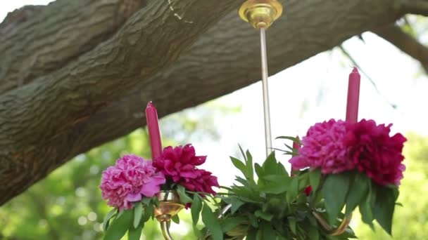 Kerzen hängen, die mit zarten Blumen geschmückt sind. Hochzeit im Garten, Park. außerhalb der Trauung. — Stockvideo