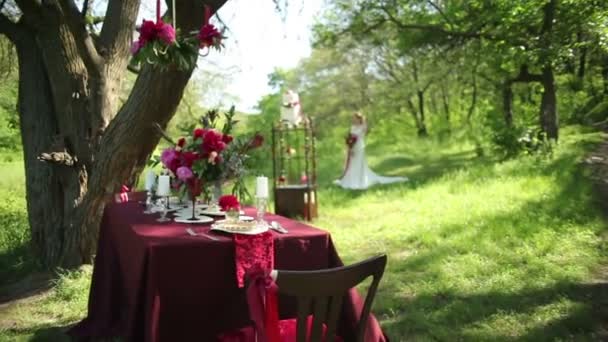 Buiten bruiloft tafel decoraties en jonge bruid met een mooie bruiloft boeket van bloemen in handen — Stockvideo