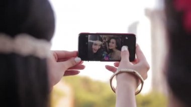 Genç kız iki Smartphone'da fotoğraf çekme. Genç bayan arkadaşlar eğlenmeye selfie çekerken. Kadınlar mutlu yüzler yapmak