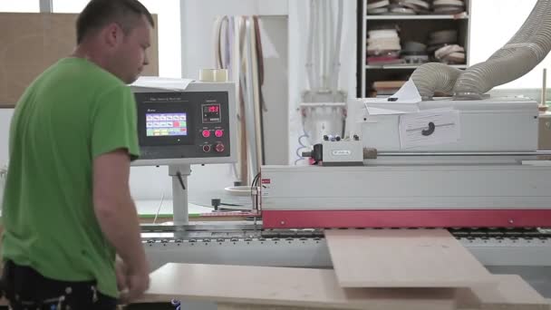 Trabajador de la madera poniendo la plancha en la máquina de carpintería . — Vídeo de stock