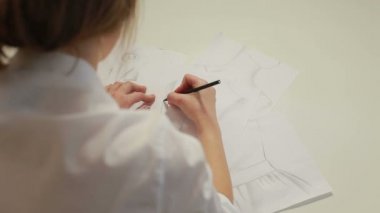 Kadın moda tasarımcısı giyim için skeçler atelier içinde çizim.
