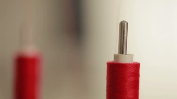 Sewing bobbin being wound up on a sewing machine with red thread. Machine in clothing industry production. Close up. — Stock Video