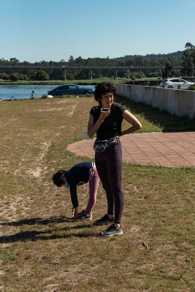 Beyaz Kadın Kızıyla Nehir Kenarındaki Parkta Yoga Yaparken Telefonla Konuşuyor — Stok fotoğraf