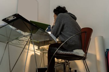 Genç bir kadın evde bilgisayar ve kağıtlarla çalışıyor..