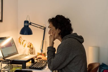 Genç kadın evde bilgisayar ve mavi lambayla çalışıyor..