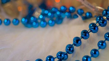 Hafif arka planda mavi noel boncukları, bir çelenk ışıklarıyla aydınlatılıyor. Kartpostal şablonu. Noel arkaplanı. Mesaj için yer. Seçici odak.