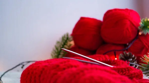 Agulhas de tricô com um produto vermelho no fundo das bolas na decoração de Ano Novo. Faça você mesmo tricô de uma camisola de Natal. Preparando-se para celebrar o ano novo e o Natal. — Fotografia de Stock