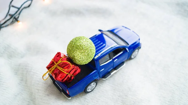 Regali di Natale nel bagagliaio di una macchina blu giocattolo su uno sfondo chiaro. Consegna di regali in auto al destinatario. Prepararsi per il nuovo anno e il Natale. — Foto Stock