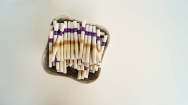 Hafif arka planda tütün ısıtma sistemi için birkaç çubuk. Kül tablasında kullanılmış çubuklar. Tütünü yakmaz, ama ısıtır. Modern sigara dünyasındaki teknolojiler. Üst görünüm.