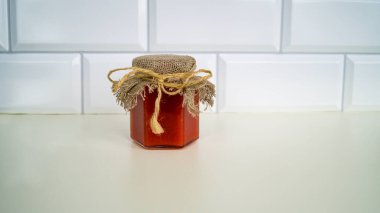 Cam bir kavanozda, arka planda çuval bezi kapağı olan organik sıvı bal. Bal-ahududu suflesi kendi prodüksiyonumuz. Sağlıklı beslenme.