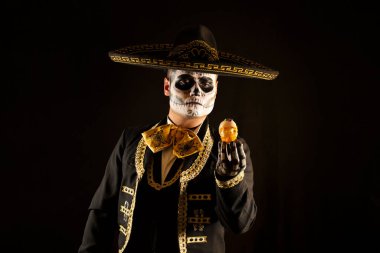 Mexican charro holding a candy skull in his hands clipart