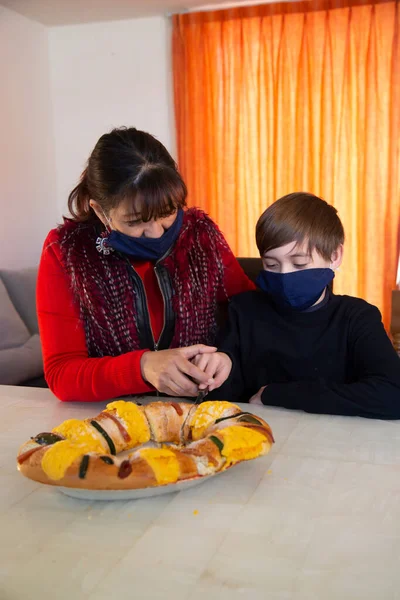 Aile geleneksel Rosca de Reyes 'i paylaşır. Çocuk kralın vida kekinde oyuncak bebek buluyor.