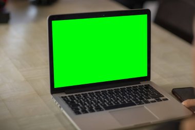 Ev işi alanında yeşil ekranlı bir laptop. ev ofisi.