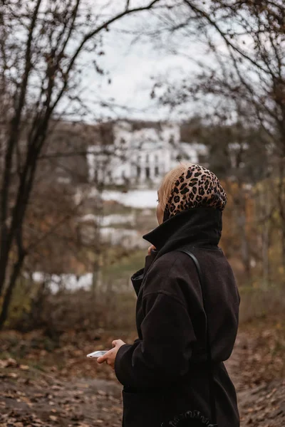 Fiatal nő leopárdsálban egy őszi parkban és kastélyban — Stock Fotó