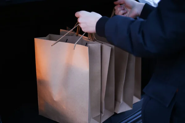 Un jeune homme met des sacs à provisions en papier dans le coffre d'une voiture — Photo
