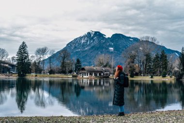 Sırt çantalı ve kırmızı bereli bir kız dağlara bakıyor.