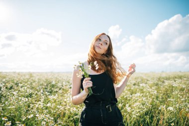 Papatya tarlasındaki kızıl saçlı kız.