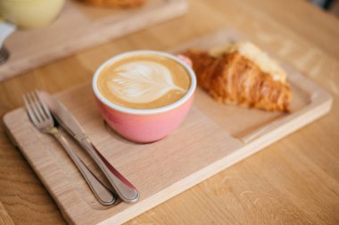 Ahşap arka planda kahveyle birlikte lezzetli kruvasanlar.